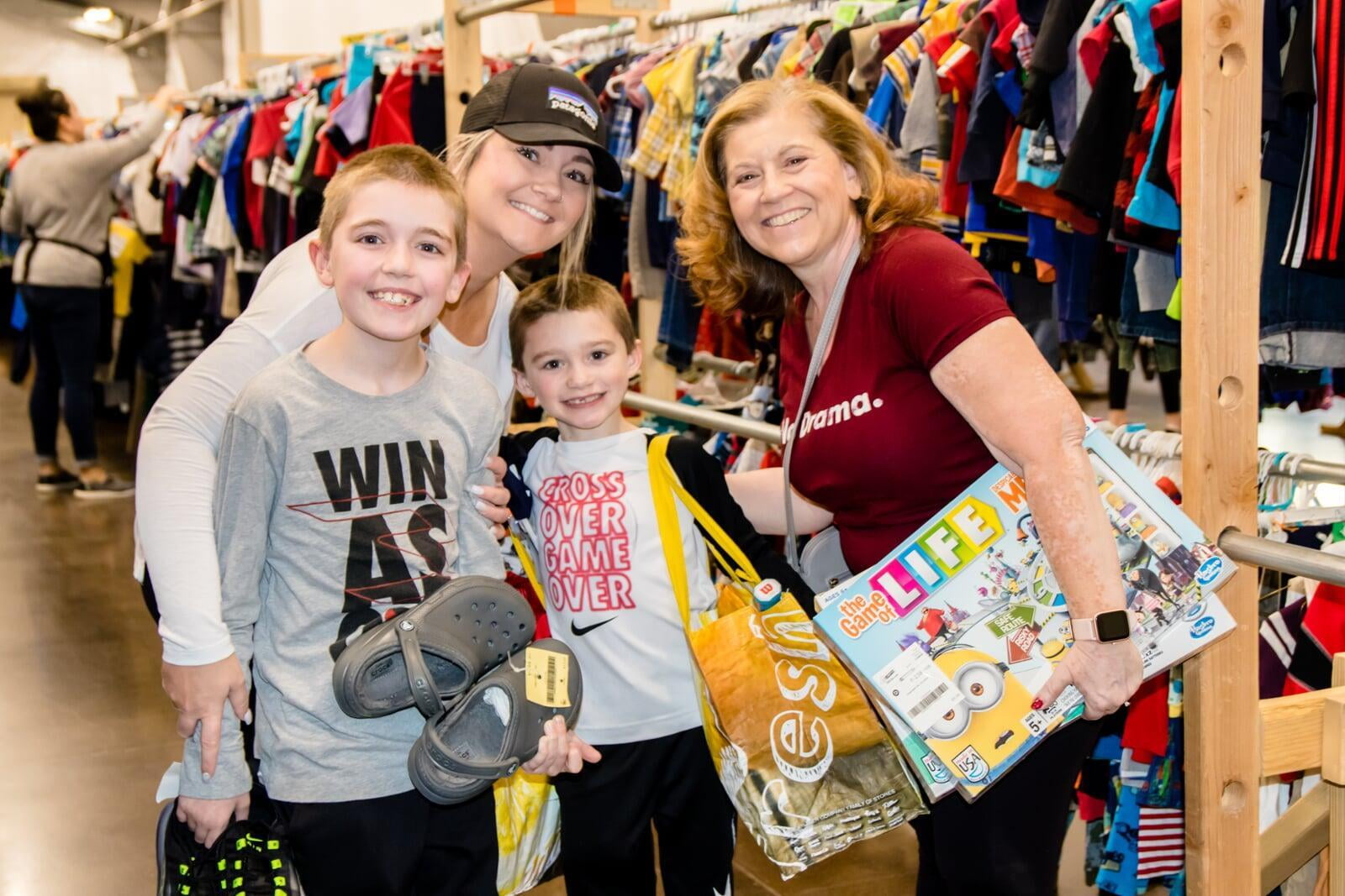 A mom, grandma, and her two grandkids stand in the clothing section for a happy family photo.